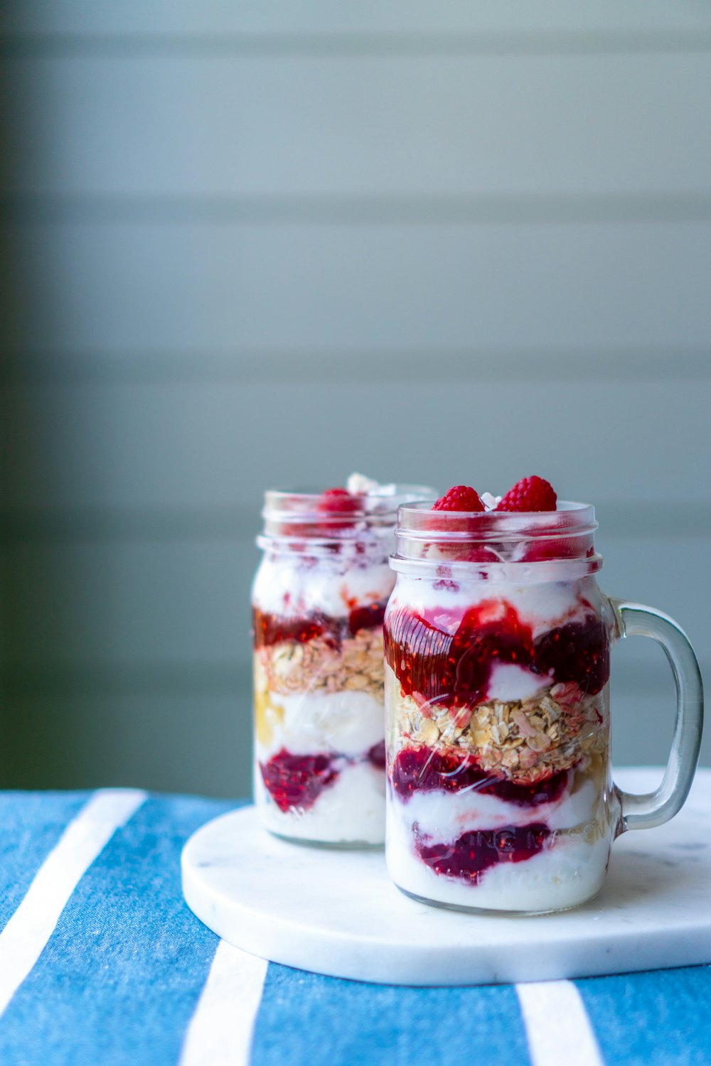 Dois potes com camadas de iogurte e frutas vermelhas