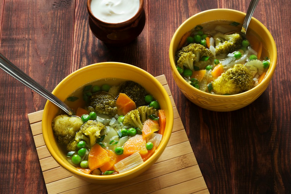 Duas tigelas de sopa de legumes com ervilha e brócolis